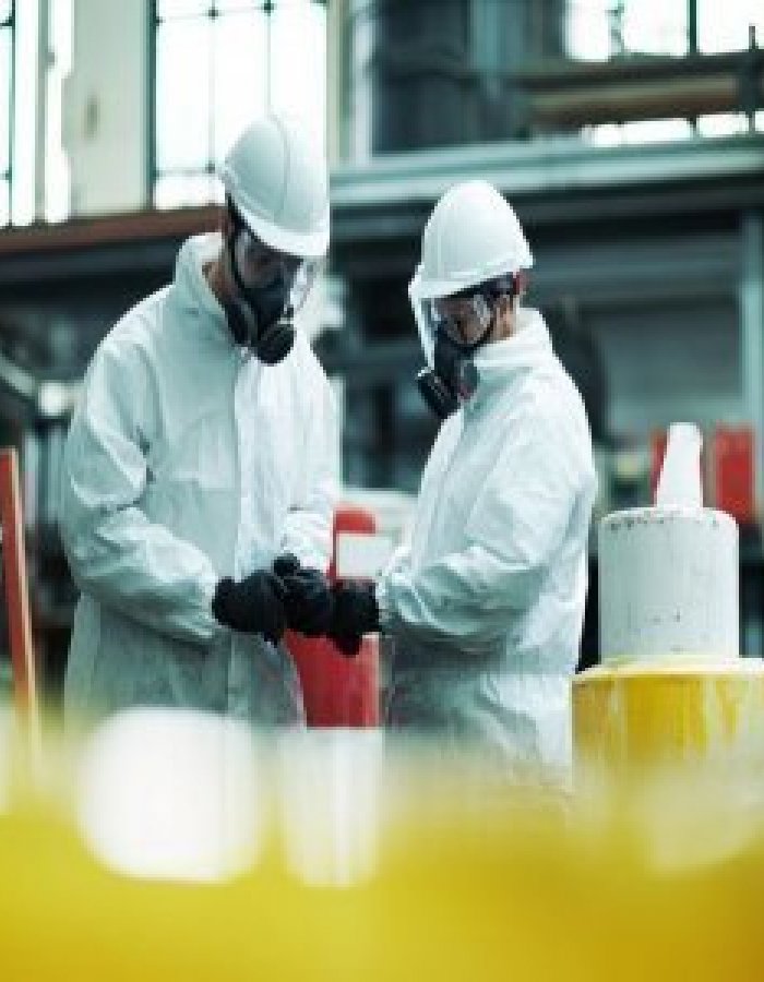 Two workers undergoing quantitative respirator fit testing in a manufacturing facility